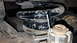 1995 Ford Bronco - A close-up view of a vehicle's suspension coil spring and mounting hardware, showing dirt and wear.
