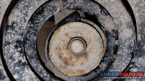 Close-up of a rusty bolt head on a vehicle's suspension coil