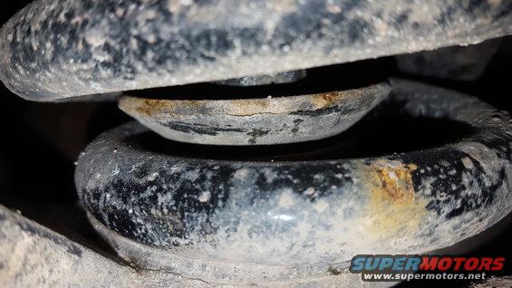 Close-up of a rusty suspension spring and metal mount with dirt and grime