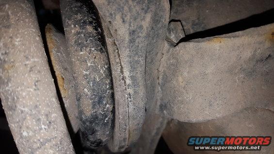 Close-up of a dirty suspension part, possibly a shock mount or control arm bushing