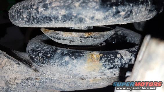 Close-up of a vehicle's suspension spring and mount with rust