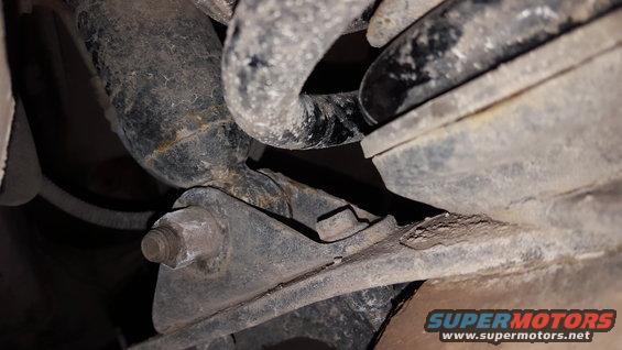 Close-up of rusty vehicle suspension parts, including a shock absorber and mounting bracket