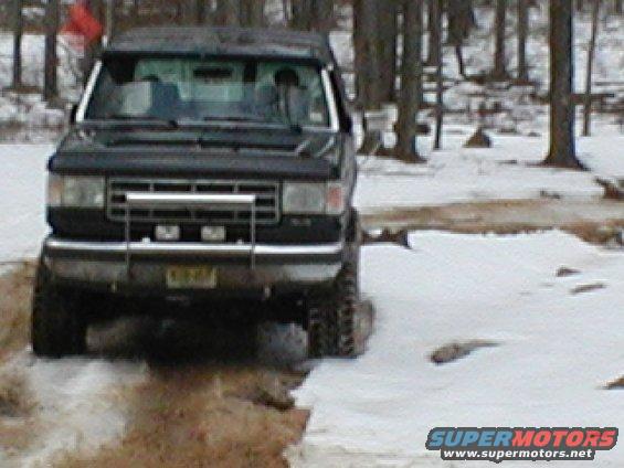 Black SUV with a chrome grille guard driving in snow, front view