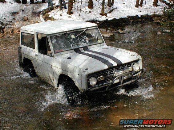White SUV with black racing stripes driving through water