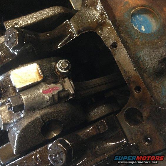 Close-up of engine block, crankshaft, and connecting rod with oil. Part number visible