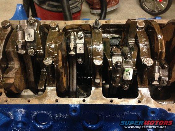 Engine crankshaft with numbered connecting rods, some with white labels
