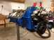 1979 Ford Bronco - Engine block painted blue, mounted on a stand for rebuild. Components like the water pump and pulley are attached.