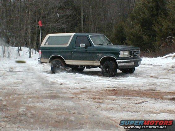 Dark green and white Ford Bronco driving in snow