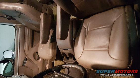 Tan leather bucket seats and center console with cup holders, viewed from driver's side