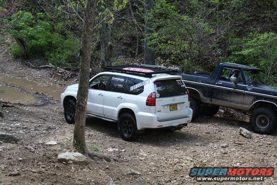 1979 Ford Bronco parked on a dirt trail with a white Lexus SUV