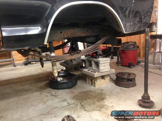 Rear axle and leaf springs removed from a black vehicle, supported by blocks