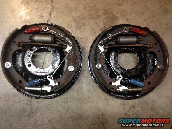 Two drum brake assemblies with shoes, springs, and wheel cylinders. One assembly is on the left, the other on the right