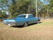 1972 Ford Ranchero - A blue and white 1964 Pontiac Grand Prix sedan is parked on a grassy field with trees in the background.