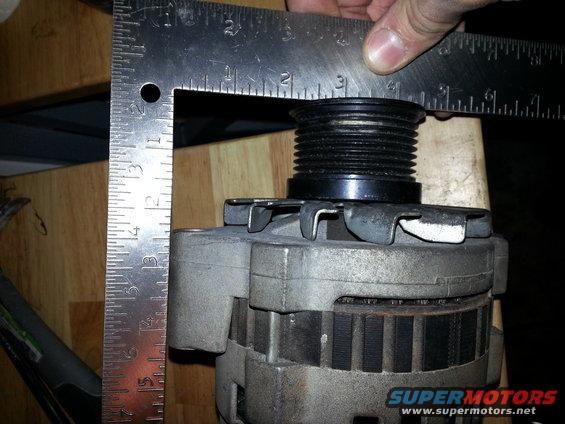 Alternator with a metal ruler measuring the pulley diameter. Text reads SUPERMOTORS