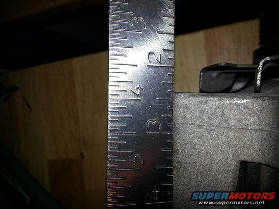 Metal part next to a ruler showing measurements in inches