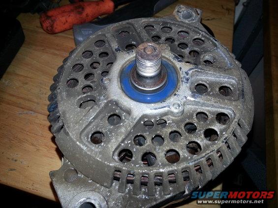 Close-up of a used alternator with a blue ring around the pulley shaft