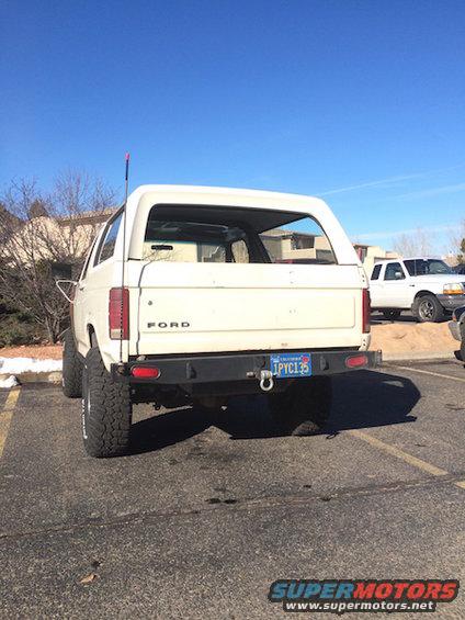 White Ford Bronco parked, rear view. California plate IPYC135. Another white truck is parked nearby
