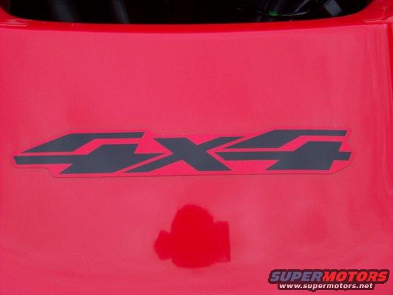 Red surface with a dark grey 4x4 decal. A small red reflection is visible below the decal