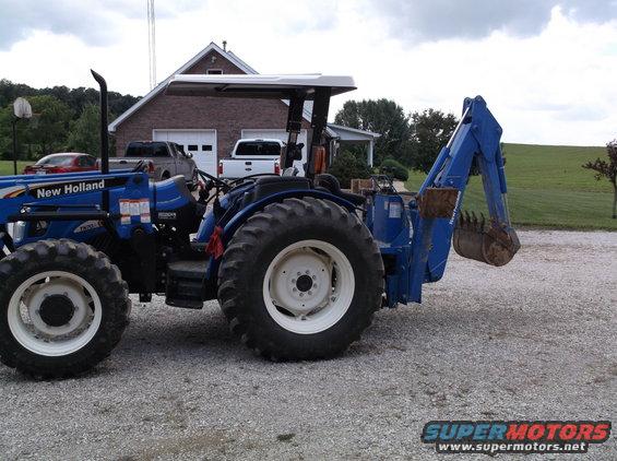 Blue New Holland tractor with a blue backhoe attachment on the rear