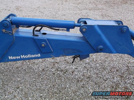 Blue New Holland backhoe attachment with hydraulic cylinder