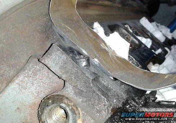 Close-up of engine block with a metal gasket piece and white rags