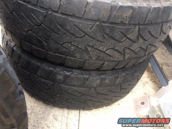 Stack of four black tires with aggressive tread patterns