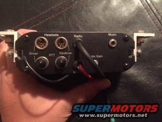 Hand holding an audio intercom unit with ports for headsets, radio, and music