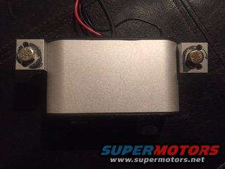 Silver intercom unit with red and black wires attached to metal brackets with bolts