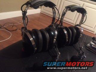 Two pairs of black over-ear headphones with metal headbands sit on a dark mat