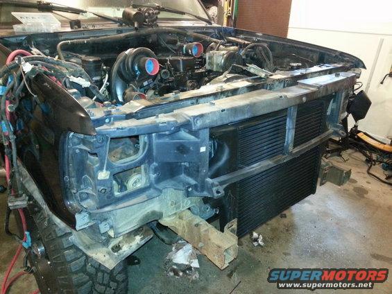 Front end of a vehicle with engine exposed, showing twin turbochargers and wiring