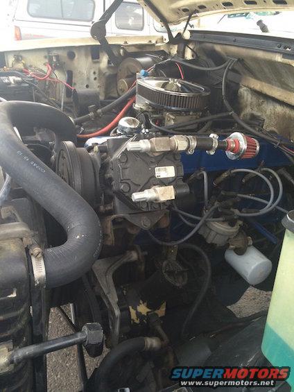 Engine bay with air filter, carburetor, and AC compressor visible
