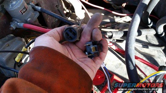 Hand holding a male and female electrical connector near engine wiring