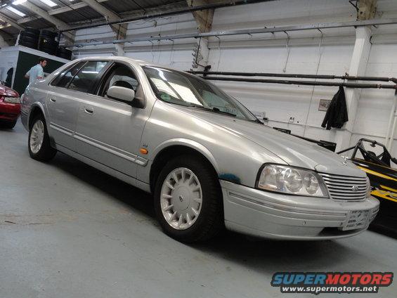 1999 Ford Fairlane sedan, silver, parked indoors. Front grille and headlights visible