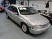 1999 Ford Fairlane - A silver sedan is parked indoors next to other vehicles.