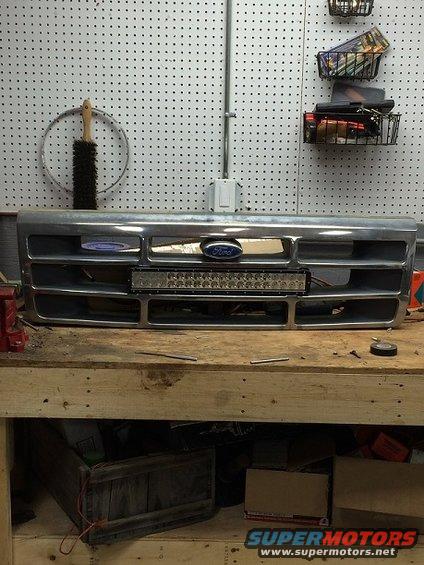 Ford grille with blue oval badge and LED light bar mounted on a workbench