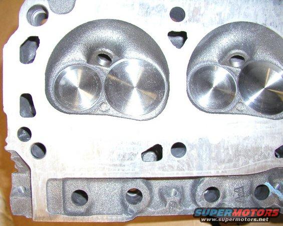 Close-up of an engine cylinder head with two valves visible in each combustion chamber