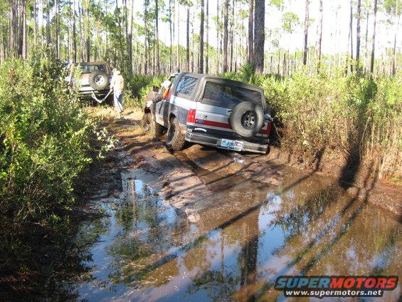 Ford Bronco stuck in mud with spare tire on rear door, two-tone paint, and a license plate