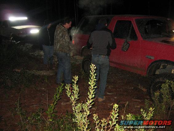 Red 1994 Ford Bronco parked at night with people nearby