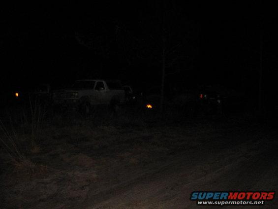 White SUV parked at night with another vehicle visible in the distance