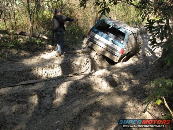 Teal and white 1994 Ford Bronco stuck in mud, rear view
