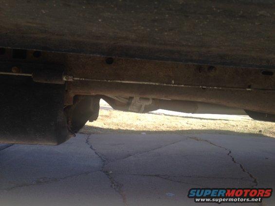 Underside view of rusty vehicle frame, exhaust, and suspension components