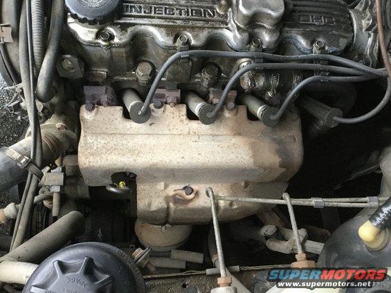 Engine bay with visible spark plug wires and exhaust manifold. Text 'INJECTION' is visible on the engine cover