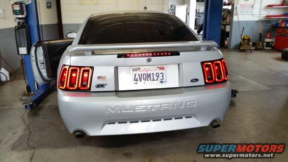 Silver 2000s Ford Mustang GT rear view, showing aftermarket LED tail lights and California plate 4VQM193