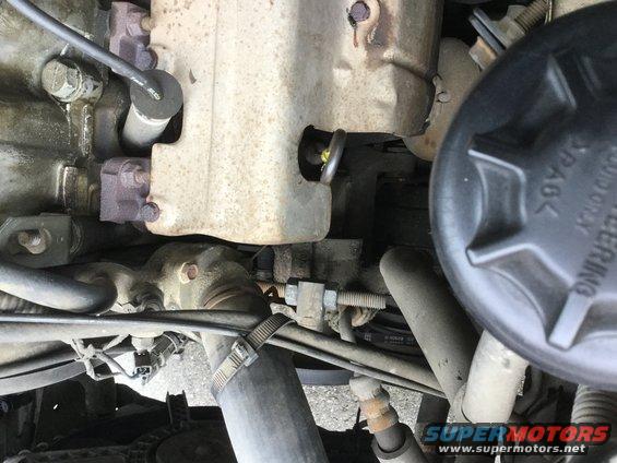 Close-up of engine bay with hoses, metal components, and a black cap labeled 'POWER STEERING'