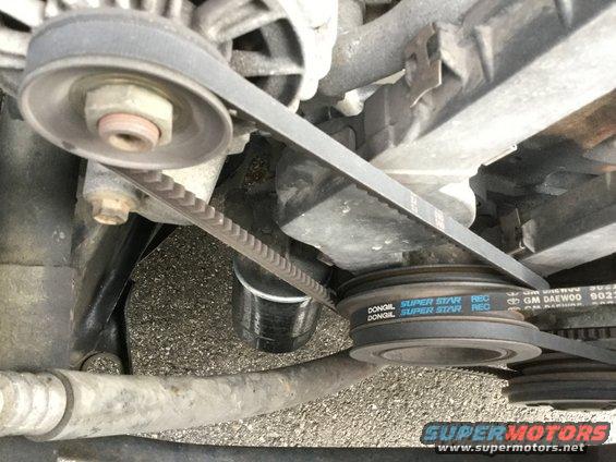 Close-up of engine belts and pulleys, one belt has 'GM DAEWOO' text