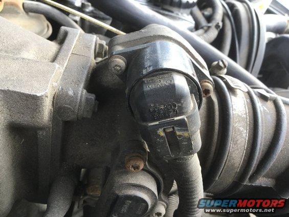 Close-up of a throttle body with part numbers visible