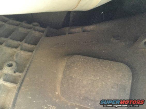 Underside of vehicle part with embossed text and grid pattern