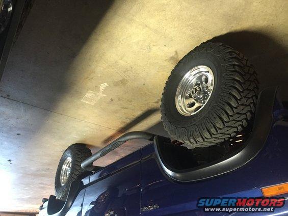 Blue SUV with large off-road tires and chrome rims, parked indoors