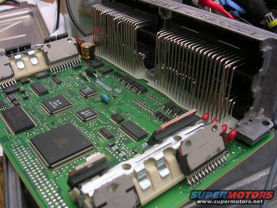 Close-up of an engine control unit's circuit board with many chips and a large heatsink