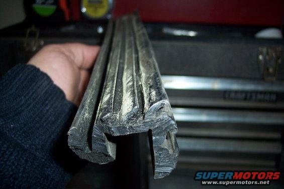 Rubber slider gasket with dust, held by a hand wearing a dark sweater. A toolbox is in the background